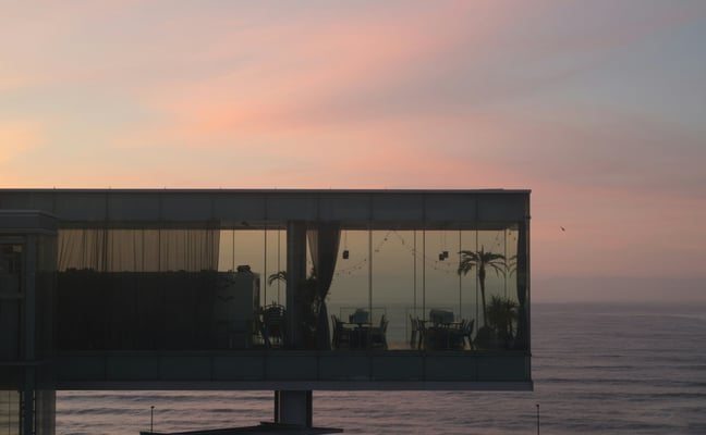 Glass house at pink sunset over the ocean