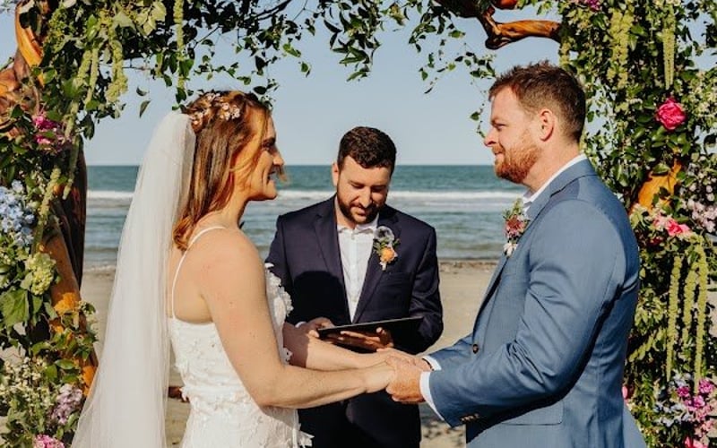 Vows at the floral arch on the beach